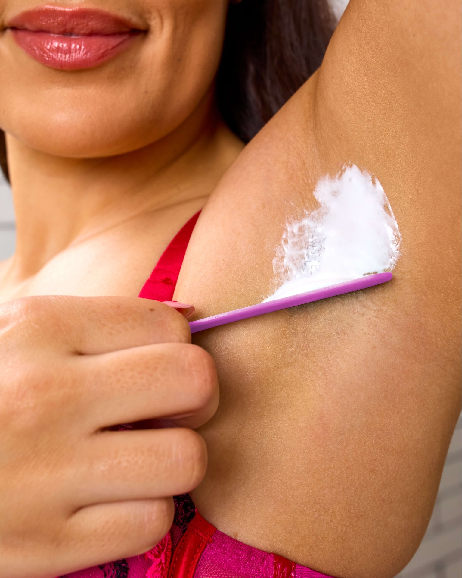 Woman applying hair removal cream on underarm, showcasing smooth, irritation-free skin for effective skincare.