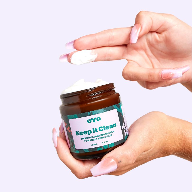 Hands holding a jar of 'Keep It Clean' mango cleansing butter, suitable for all skin types and made with clean ingredients.