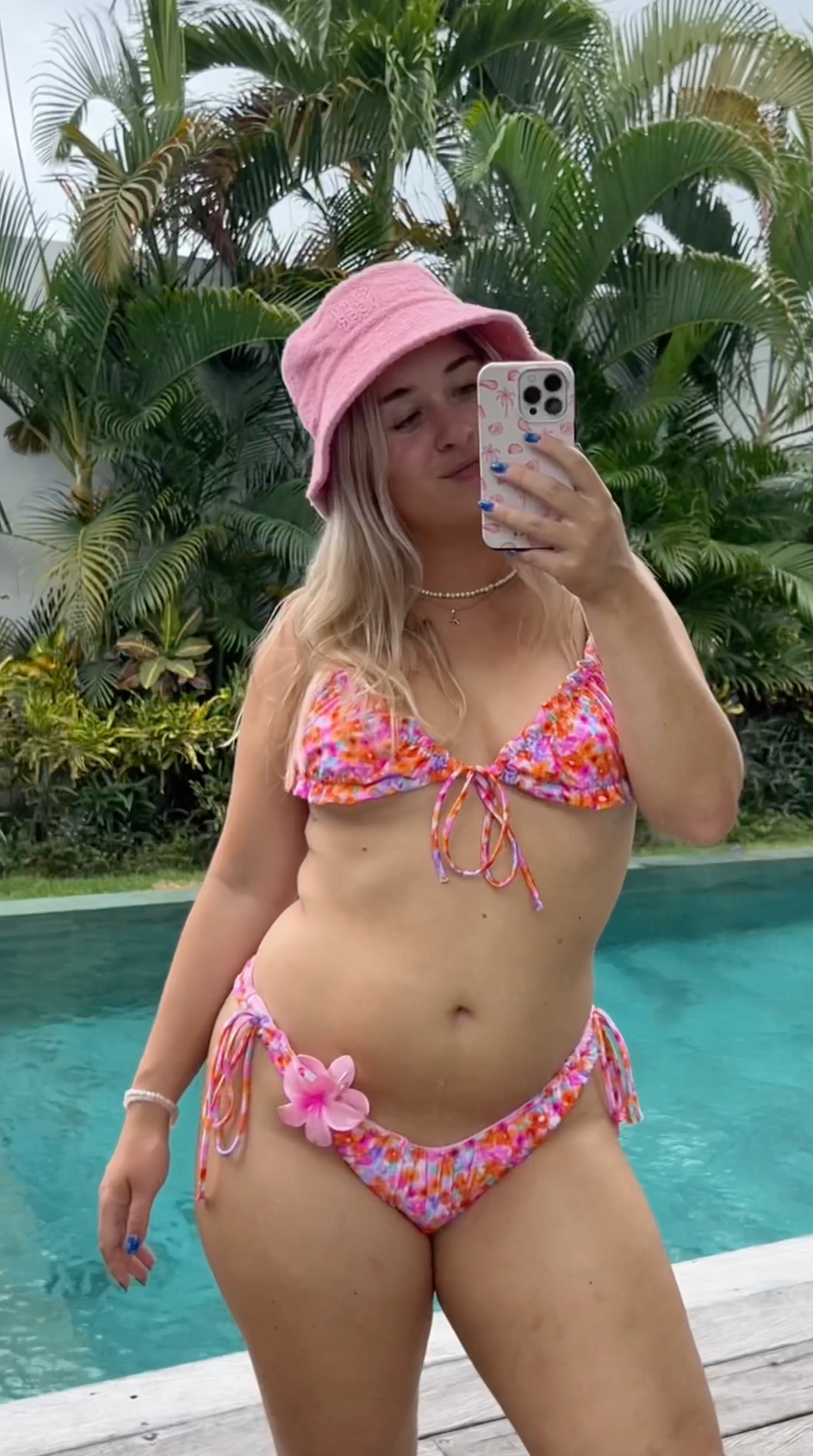 Woman in a colorful bikini by the pool, embodying confidence and summer vibes.