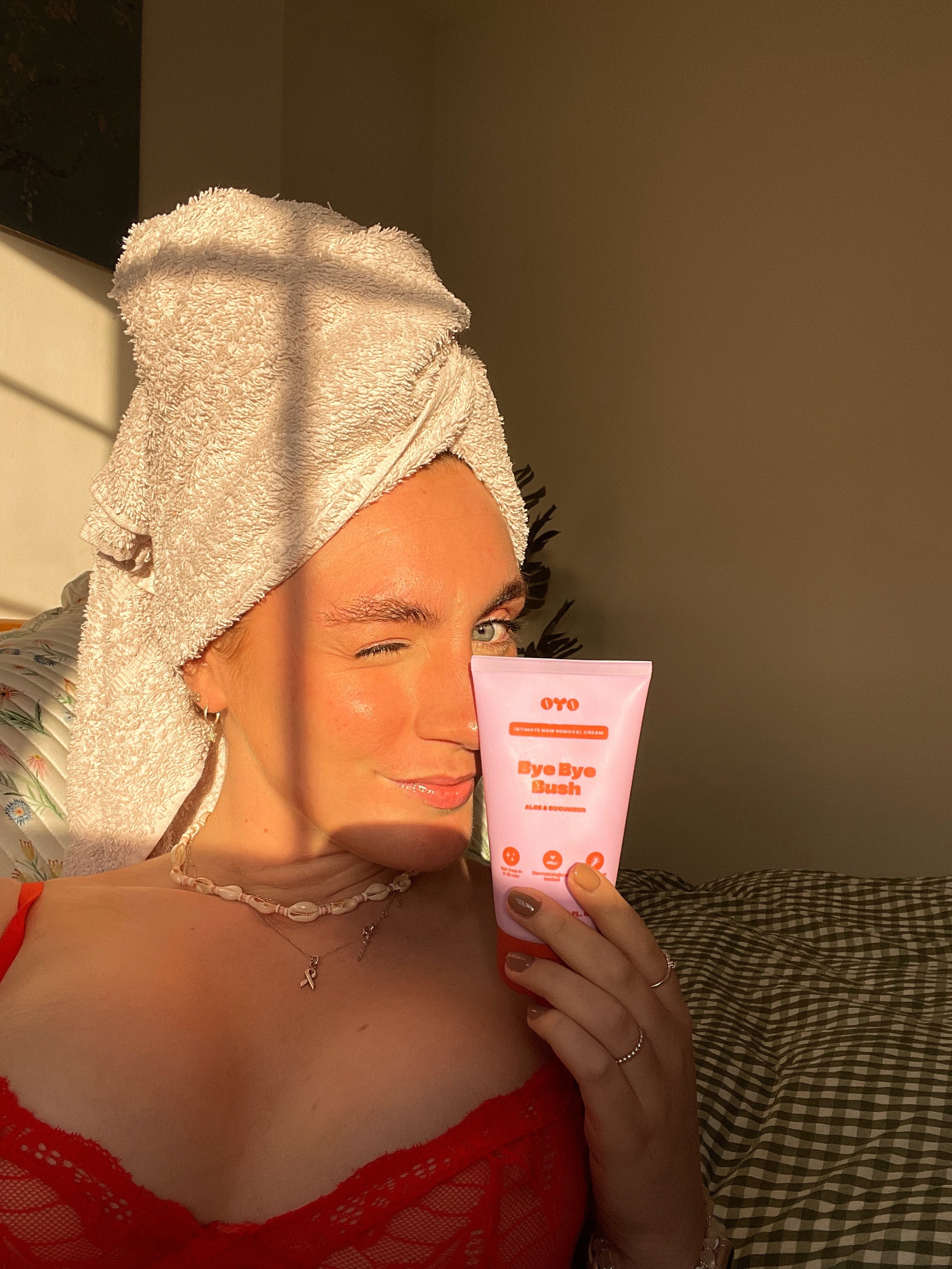 Woman with a towel and skincare product, promoting natural skincare for intimate areas, soothing and nourishing.
