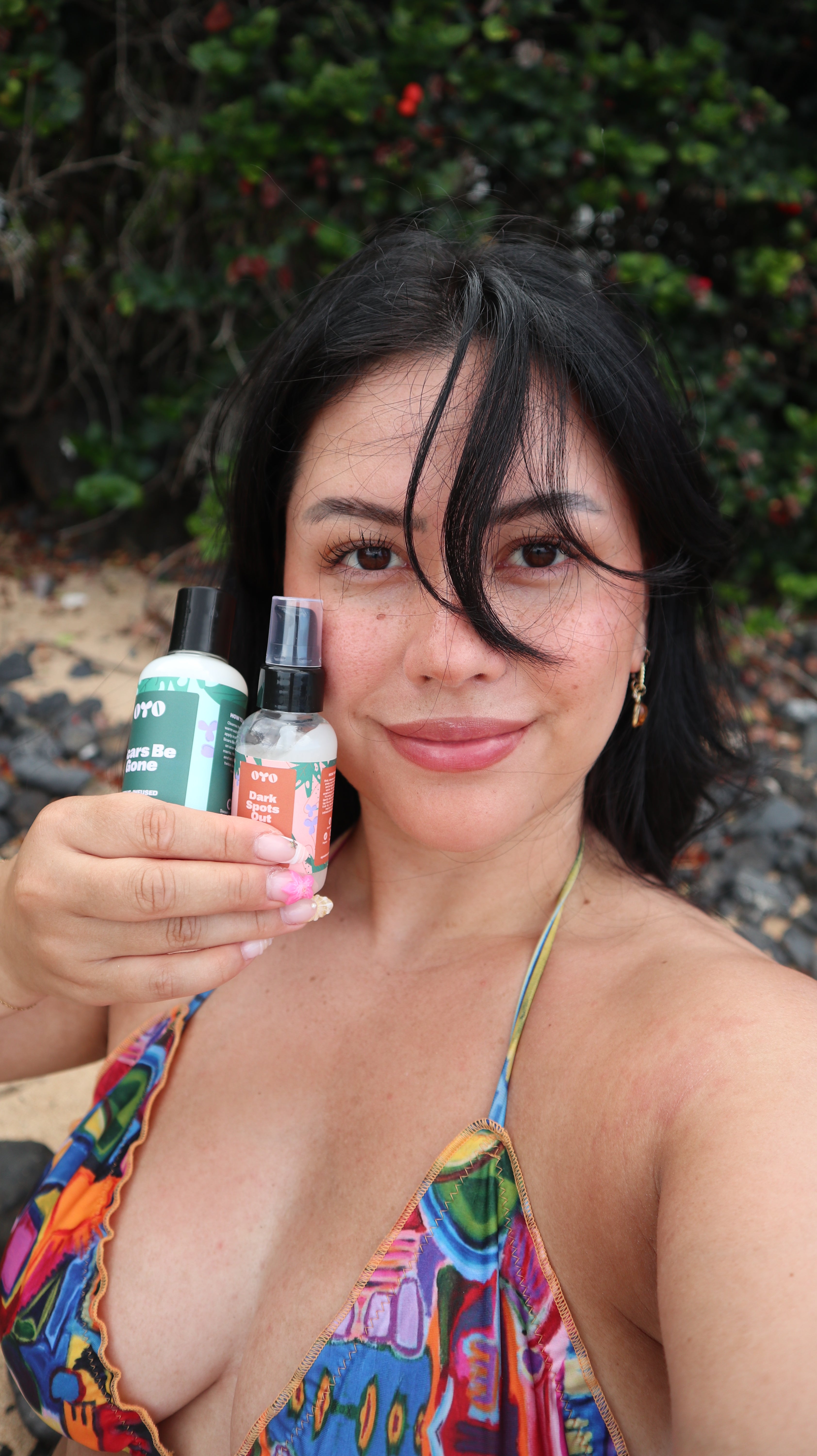 Woman holding natural skincare products near the beach, showcasing effective skincare for sensitive areas and skin routines.